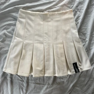 Vit plusserad kjol - En vit plisserad kjol från Bershka i bra skick. Storlek XS, ca 32cm i midjemått.