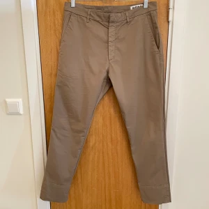 Beiga Hope-chinos, M48/W40 - Ett par tunnare chinos/byxor som en familjemedlem växt ur. Plagget är i bra skick och utan skavanker. Det kommer från ett djur- och rökfritt hem. OBS: Byxorna är en storlek för stora för personen på sista bilden och de är uppvikta. Frågor? Skicka pm!