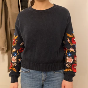 Blå stickad tröja med blommiga detaljer på ärmarna - Använt ett par gånger men är fortfarande i perfekt form