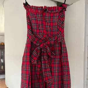 Skotsrutig klänning med rosett - Skotsrutig klänning med rosett i ryggen.