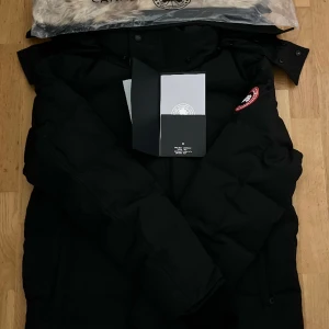Canasta Goose jacka  - En svart Canada Goose-jacka i storlek M är både stilren och funktionell. Den har en avtagbar huva med en mysig pälskant och flera fickor praktisk förvaringar. Perfekt för att hålla dig varm under vinter. Pris kan diskuteras 