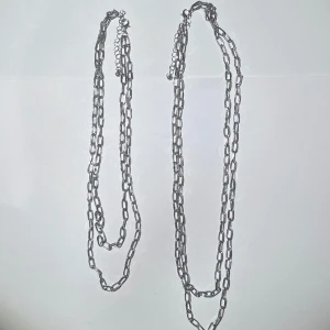 2st kedje halsband - 2st kedje halsband med 2 kedjor som sitter ihop. det ena är längre än det andra med några cm. de går också att justeras, på bilden är de spänt kortast. silver materialet är ganska gråaktigt men i helt okej skick. frakt 15kr med swish, eller köp nu.