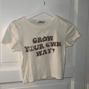 Beige croppad t-shirt med brun text. 