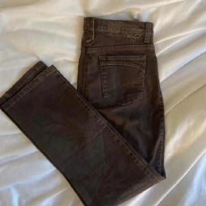 Byxor med snygg tigerdetalj - Bruna byxor med ascool detalj. Köpta second hand, säljer pga för små. Felfria förutom att gylfen tyvärr är trasig, därav priset.