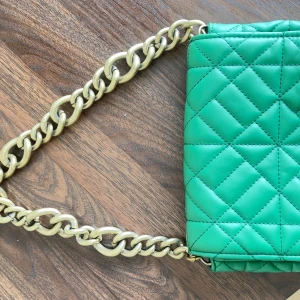 Grön väska från Zara - Grön handväska från Zara i mycket fint skick. Väskan är använd men väl omhändertagen och ser nästan ny ut. Stilren design med axelrem. Perfekt för dig som vill ha en kvalitetsväska till ett bra pris.