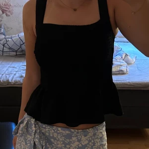Svart volanf topp - Svart linne med volang och bredare band! Är resår vid bysten och framsida men annat tunnare material på baksidan😊 har sytt om banden då de var för långa men inget som syns när man bär den på💞