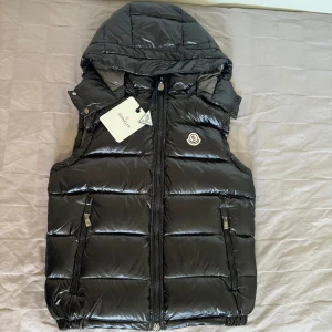 Moncler väst - Säljer min Moncler väst som jag aldrig använt. Tag finns som ni ser på bilden och QR och NFC funkar. Väldigt hög 1 av 1 kvalitet. Luva går att ta bort och sätta på 