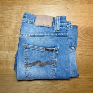 Nudie Jeans - Tjo! Nu säljer jag dessa skit snygga Nudie jeansen, dom har väldigt fin ljus blå färg och är slim fit. Skick: 10/10 inga defekter👍. Nypris: 1500kr❌, mitt pris: 499kr✅. Jag kan skicka mer bilder på passform och annat så det är bara att skriva🙌!