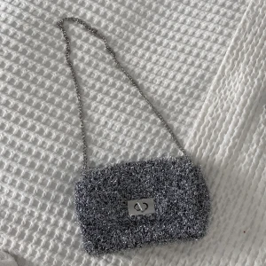 Glittrig väska - Fin glittrig väska i mjukt tyg. Helt oanvänd och går att justera både till lång och kortare kedja!