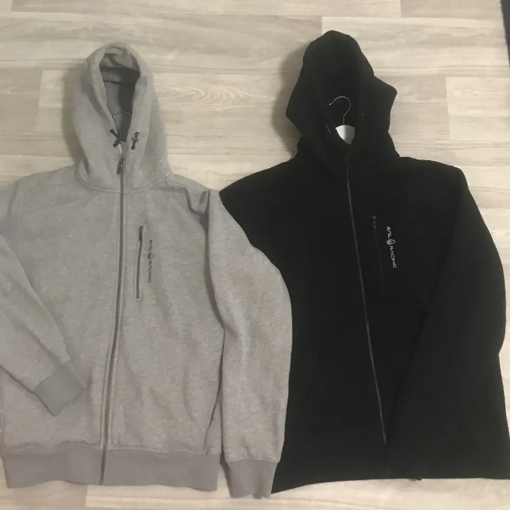 Hejsan,  Säljer två styckna Sail Racing Zip hoodie (Xl) i färgen svart och grå som endast är använda 1-2 gånger, båda är som nyskick. Säljes pågrund av att jag har för många klädder liggandes och detta var ett spontant köp.  Säljer båda för 900kr !!. Hoodies.