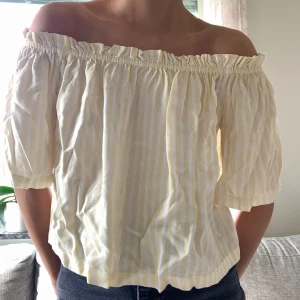 Gul- och vitrandig off-shoulder topp - Enkelt att välja var på eller av axlarna du vill ha toppen. Bra resår.