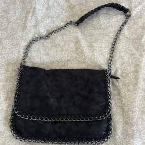 svart väska med kedja  -  Glittrigt / skimrigt material inga skador använd senast förra sommaren säljer på grund av används inte kedjan är justerbar nypris 499 säljer för 300