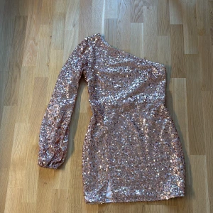 Glittrig off-shoulder klänning - Miniklänning  i rosé guld från NA-KD med off-shoulder. 🩷 Ärmen är lite mer som en ballongärm 