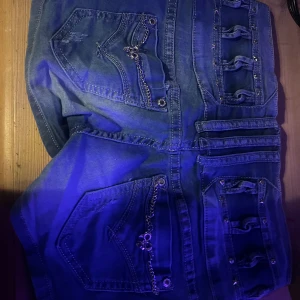 Blåa jeansshorts med kedjor och nitar - Jätte gulliga jeansshorts med detaljer <3  Kan själv inte ha dem, men skulle tro de är mid waist! Skriv till mig om frågor eller mer bilder. SKRIV INNAN DU TRYCKER PÅ KÖP NU