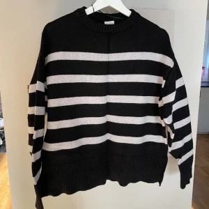 Stickad tröja - Stickad tröja, knappt använd, något tvättpåverkad på den vita färgen annars utan anmärkning. 