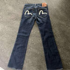 Jättefina Evisu jeans i bootcut modell, lowwaist. Midja: ca 37 innerben: ca 82 Säljes då dom tyvärr är lite långa på mig som är 160💕 Är i nyskick, inte upptrampade, hål/fläckar eller några täcken på användning🫶🏻nypris 2500. Pris är diskuterbart!!!