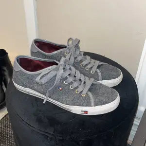 Sååå snygga låga skor från Tommy Hilfiger i perfekt grå färg. Ena skosnöret har tappat sin plastgrej längst fram (se bild 3), annars i gott skick! Skosnöret går enkelt att byta ut om man vill.