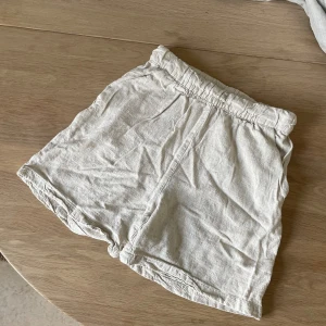 Beiga linneshorts i storlek 34  - Shorts i linneblandning med fickor fram och resår i midjan. Aldrig använda, inga skavanker. 🌸 Säljer pga tyvärr för små för mig.   Längd totalt ca 35 cm.