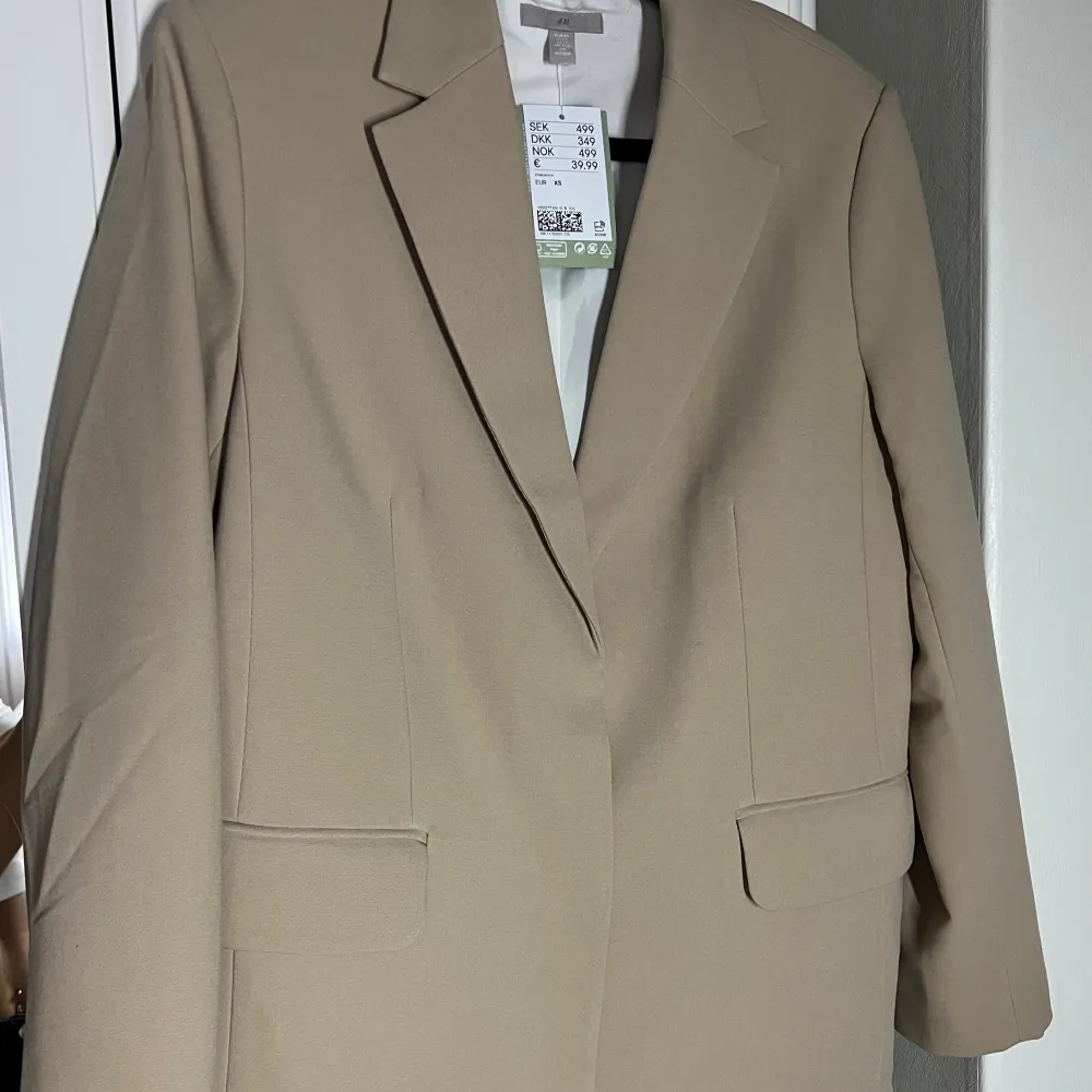 Sjukt snygg oversized beige kavaj med axelvaddar. Vit fodrad, se bild hur den ser ut när man viker upp ärmen. Rak i modellen och lite mer rejält tyg så funkar även att bära som en jacka. Aldrig använd med prislapp kvar, köpt för 500kr  . Kostymer.