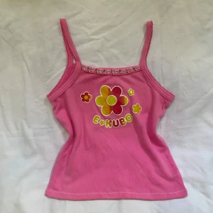 Linne  - Söt rosa linne med blommönster och texten "E*KUBO". Linnet har en spetskant vid halsen. Estimerar storleken till XS-S. 