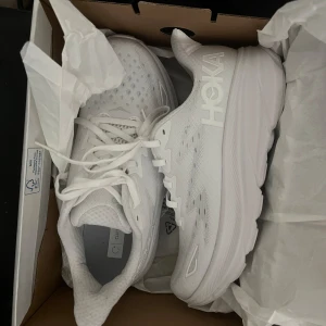 Hoka clifton 9 - Säljer dessa helt oanvända hoka clifton 9 skor i vitt. Helt nya med kartong. Storlek 39 men passar mig som har 37/38 i vanliga fall🫶🏻