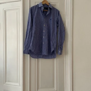 Ralph lauren skjorta - Ralph Lauren skjorta  Blå & vit rutig  Fint begagnat skick, men mindre fläck som visas i bild tre. Knappt märkbar när skjortan sitter på. 