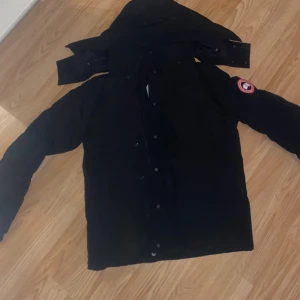 Svart canada goose jacka kort - En svart canada goose jacka som är armlängd, är i xs med passar även S/M, funkar för både tjejer och killar. Fick den i födelsedagspresent (inte min stil). Aldrig använd. Påse, paket, taggar medföljer. Pälsen ingår. Skriv vid intresse och frågor💛