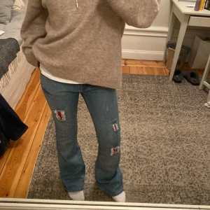 Jeans med coola detaljer - Lågmidjade bootcutjeans med skitcoola detaljer fram. Superbra skick Innerbenslängd 76cm, midjemåttet 37cm