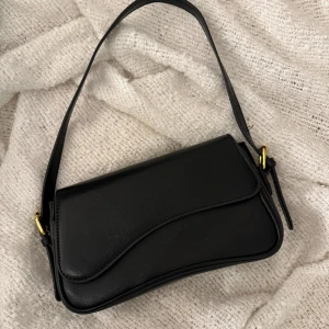 Handväska Svart - Skinväska i svart helt oanvänd!  Går att korta ner/ förlänga banden!  