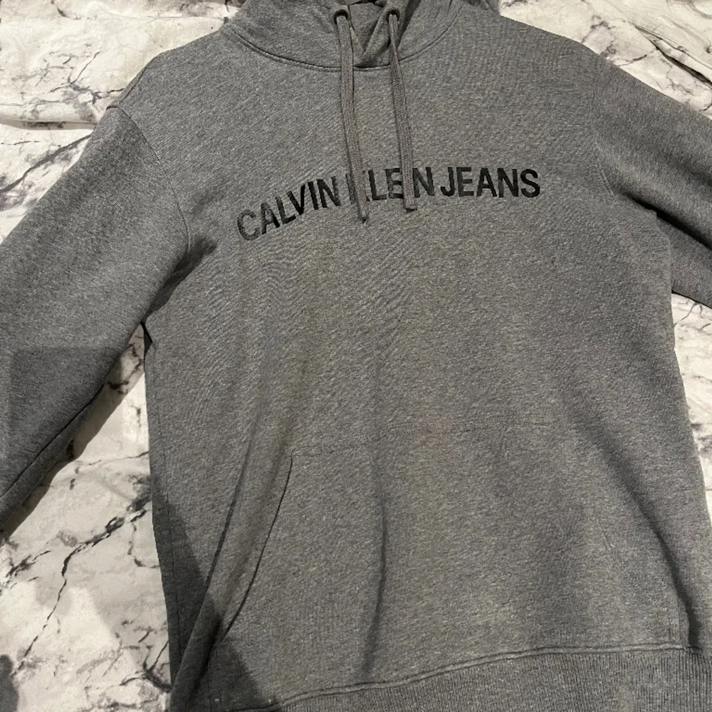 Säljer en jättefin, grå, varm hoddie från Calvin Klein Jeans i stl. S. (Någon skråma på bild 3, men ej märkbar därav priset) Använd fåtal gånger och säljer för 120kr+frakt. (Kan i vissa fall mötas upp)😊. Hoodies.