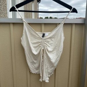 Söt vit topp från H&M i storlek S - Aldrig använd! Söt vit ”fjärils”topp som går att spänna åt i mitten på bysten. 🦋 Storlek S.