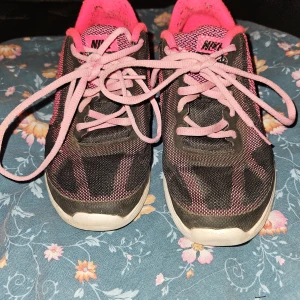 Nike träningsskor - Nike revolution 3 löparskor i svart och rosa. Mycket fint skick förutom längst ner som behöver torkas av pga smuts, namnade men inget som störs utseendemässigt Annars hela och rena