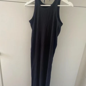 Svart ärmlös klänning - En enkel och stilren svart ärmlös klänning. Klänningen har en rund halsringning och är av normal passform. Perfekt för både vardag och fest.