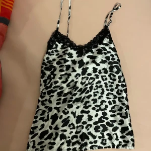 Leopardmönstrad linne topp med spetsdetaljer - En leopardmönstrad linne topp med svarta spetsdetaljer vid halsringningen. Toppen har tunna axelband och är ärmlös. Skriv till mig om ni har frågor 💕