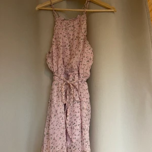 Rosa klänning med blommor - Super söt klänning i bra skickt! Klänningen har ett snöre i midjan som man kan välja att ha. Strl XS 