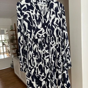 Tunika från Vila - Marinblå/vit mönstrad knälång viskos tunika/klänning från Vila. Knytband under bysten Aldrig använd.