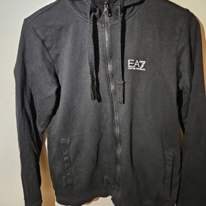 EA7 Mjukisdress  - Säljer nu min EA7 dress i bra kvalite enda nackdelen är att tröjan är lite solblekt men annars finns det inga slitage. Fraktar inom 24h📦 Hoodie är i storlek M och byxorna i storlek S. Skick 7,5/10