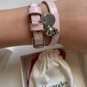 Alexander McQueen armband i färgen rosa. Lite missfärgningar där spännet sitter, syns på sista bilden. Kommer med kartong, kvitto och dustbag. 