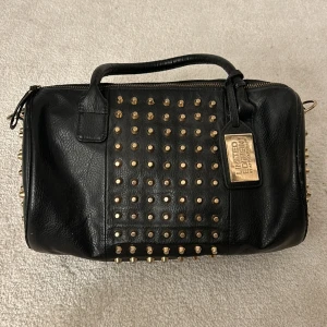 Väska med nitar  - Säljer denna coola svarta väska med nitar!!💕💕 Mått:  bredd- 32 cm höjd- 20cm