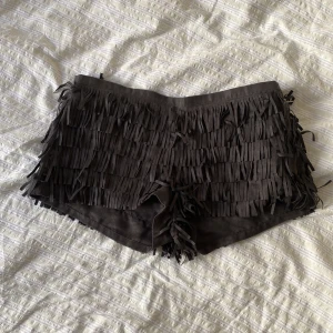 Lågmidjade shorts - Supersnygga lågmidjade shorts med fransar i mockaaktigt material. Dragkedja och knapp på sidan. Köptes på Vinted men säljer då de är för små. Strl S🤍