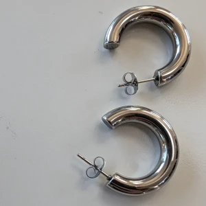 Enfärgade/silverfärgad örhängen i rostfritt stål,NY - Diameter 2.5 cm Längden 2.5 cm Bredd 2.5 cm  Ganska lite tunga Postar inom 3 dagar efter köpet 