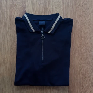 Svart piké  - Oanvänd piké med dragkedja från H&M.   Rensar ur min garderob från en hel del oanvända kläder🌼 Om du ser något mer i min profil som du gillar så skickar jag med det till dig också!😊 Fler kläder kommer! 