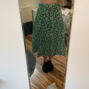 Grön och vitblommig kjol med slit på ena sidan och nästan onsynlig dragkedja där bak. Nyskick 