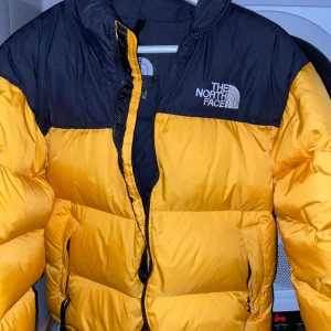 North Face Puffer 1996 Gul - Pufferjacka från TheNorthFace, modell 1996 med färgen gul. Jackan är i storlek M (Herr), person på bild är 187cm. Bra begagnat skick, någon mindre fläck på en ärm (skickar bild om det behövs). Nypris 3899kr. Pris kan diskuteras. 