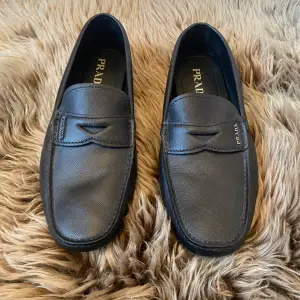 Prada Saffiano Leather  Upper with metal lettering logo applied to  Upper: Saffiano leather the leather saddle Removable insole, Rubber block sole without box  made in Italy