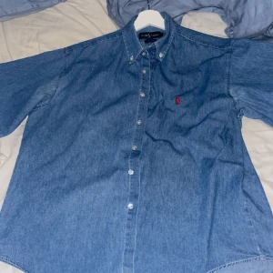 Ralph Lauren jeans skjorta - Säljer min jeans Ralph lauren skjorta då den inte går till användning, använt 3 gånger. Skick 9/10, finns lite små trådar som sticker ut men annars inget man märker. Den är True To Size, de vill säga passar som en L.