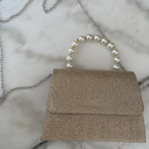 Champagnefärgad väska  - En fin oanvänd champagnefärgad väska. 