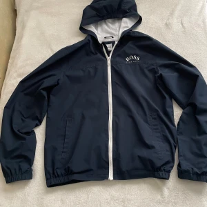 Hugo boss jacka  - Vindjacka Storlek XL i barnstorlek passar S oxå. Skick 7.5/10, väldigt bra skick ändats ett håll sån har sytts fast’ syns knappt.