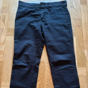Svarta byxor från Dickies - Ett par svarta slim fit byxor från Dickies. Byxorna har en klassisk design med hällor för bälte och en dragkedja.