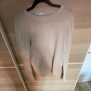 Stickad tröja - Säljer denna fina beiga tröja ifrån zara! Den har små guldiga detaljer på båda ärmars som man kan se på bilden. Endast testad och säljer för att den passade inte!🥰